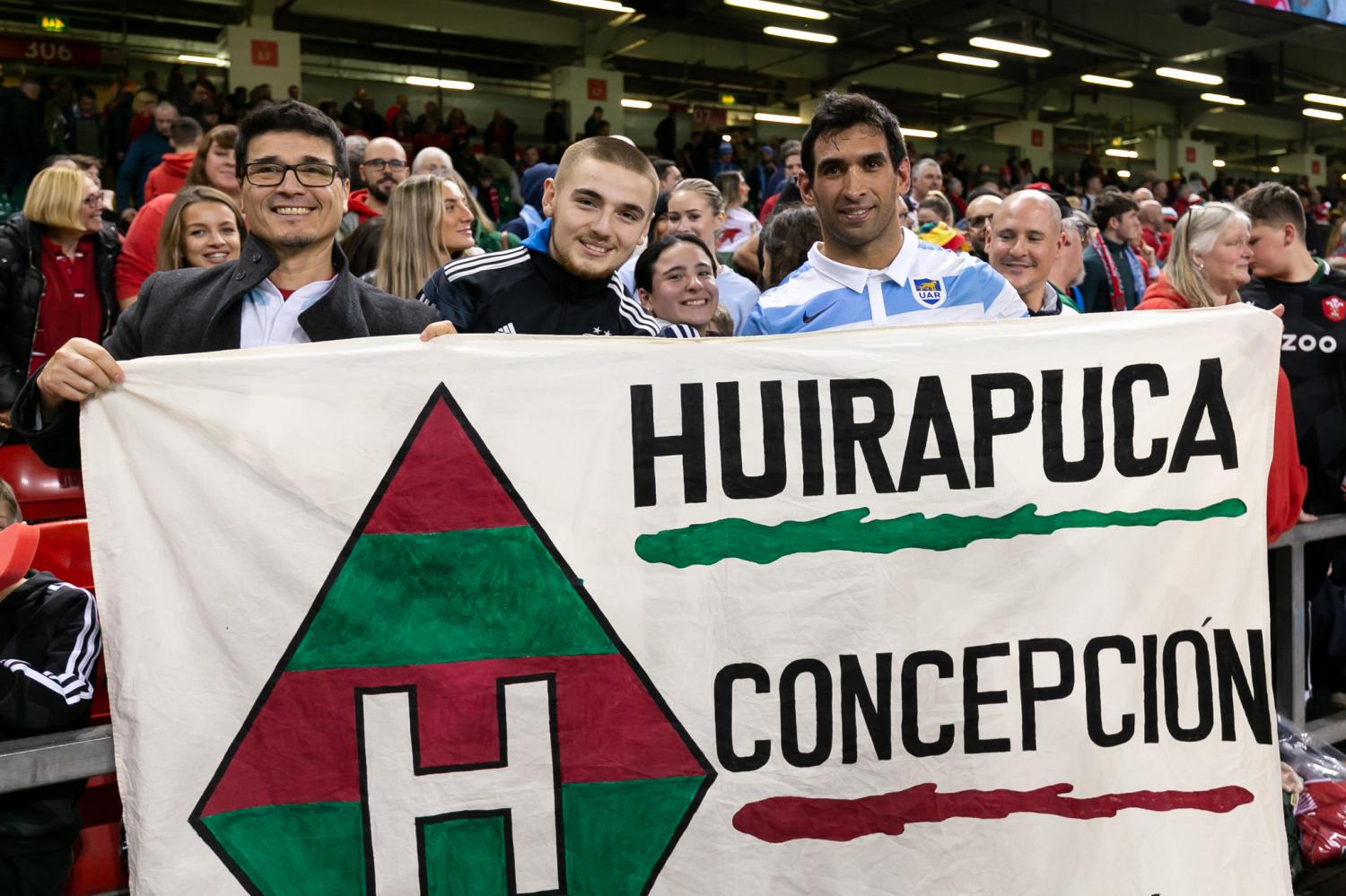 HUIRAPUCA EN CARDIFF. La bandera de Huirapuca y Concepción junto a Matías Orlando en las tribunas de Cardiff. FOTO: Prensa UAR 